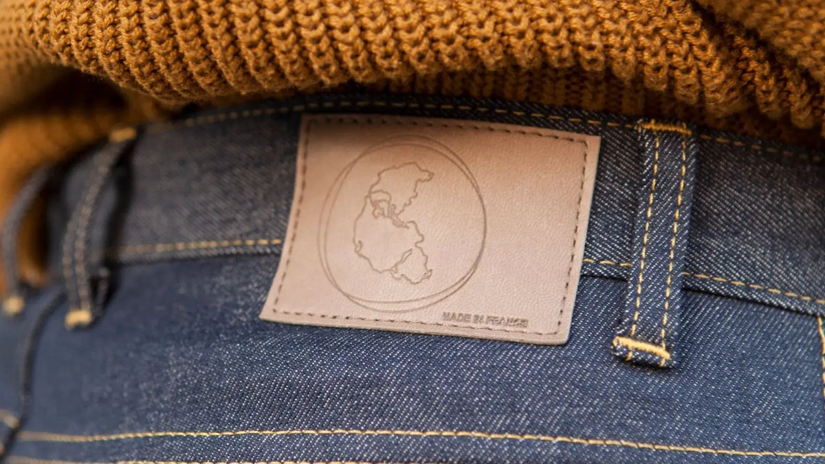 Étiquette en simili-cuir Ecclo avec le logo Pangée et la mention Made in France, au dos d’un jean brut.
