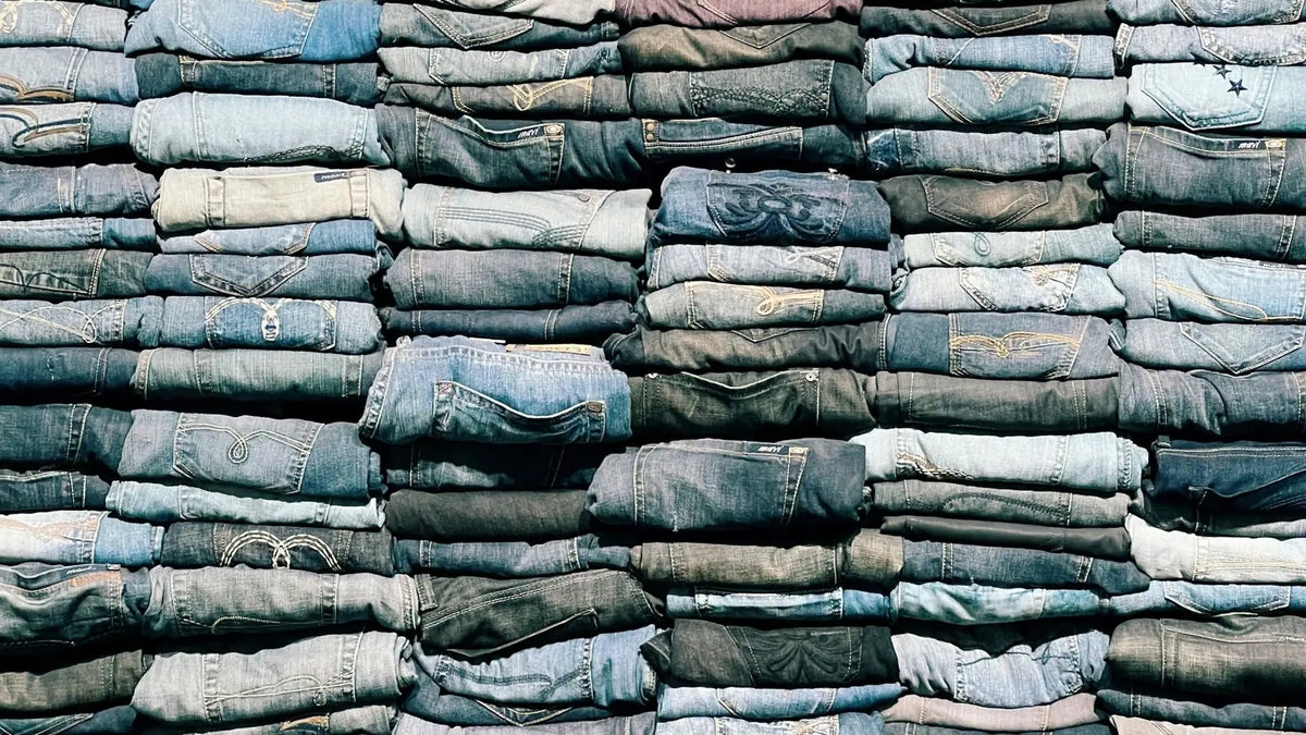 Piles de jeans délavés, symbole de la production massive de denim.
